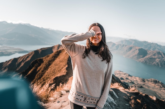 Foto brunette weißes mädchen mit langen haaren grauer pullover schwarze hose mit rechter hand bedeckt sie glücklich