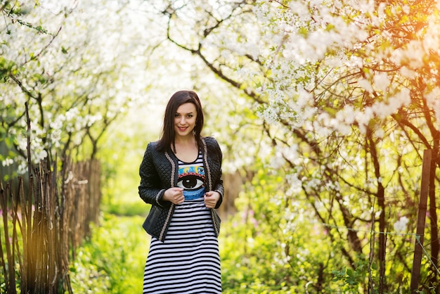 Brunettefrau an der Lederjacke warf auf Frühlingsgarten auf.