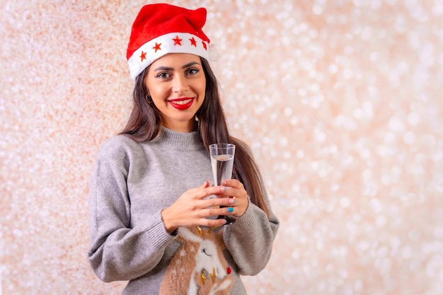 Brunettefrau im weihnachtsgrauen weihnachts- und guten rutsch ins neue jahr-strickjacke mit einem glas champagner