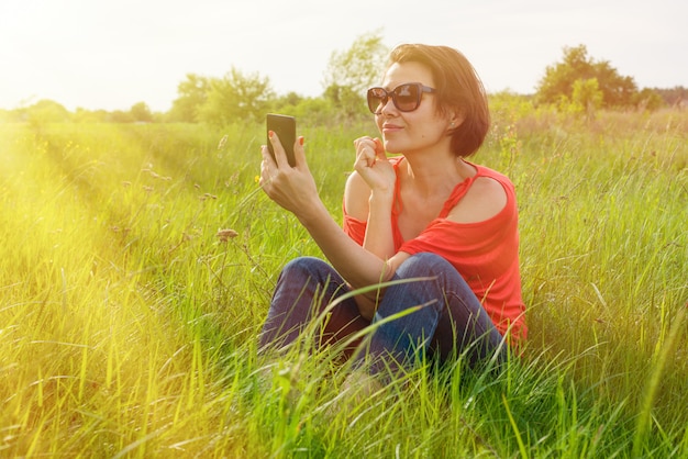 Brunettefrau mit Telefon auf dem Gras