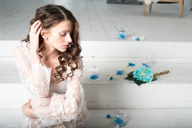 Brunettemädchen im weißen Kleid, das auf der Treppe sitzt