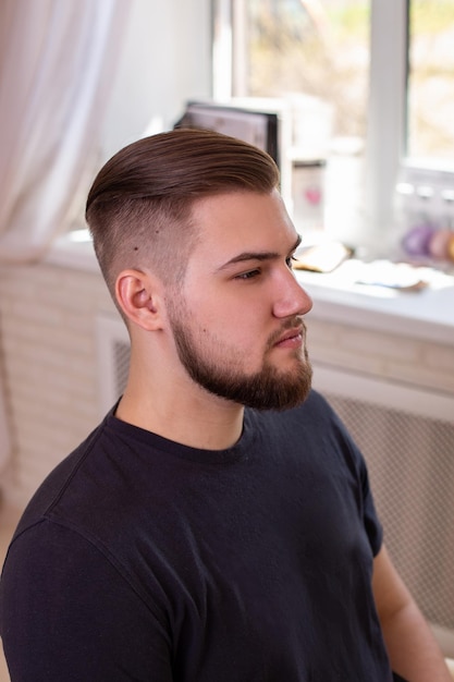 Brunettemann mit stilvollem Haarschnitt auf Friseursalonhintergrund