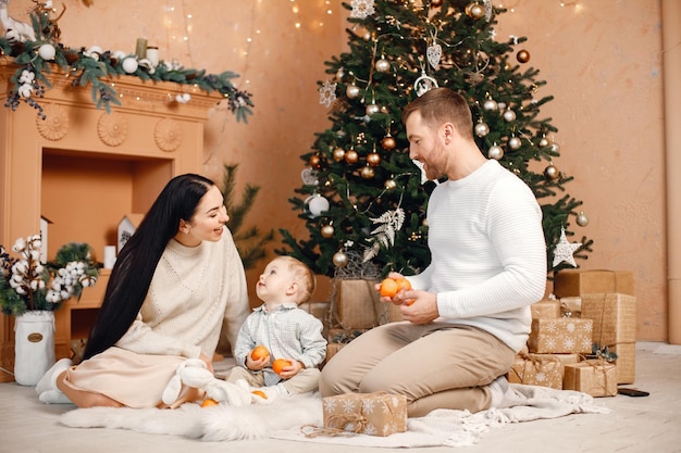 Brunettemuttervater und kleiner Sohn, die nahe Weihnachtsbaum sitzen