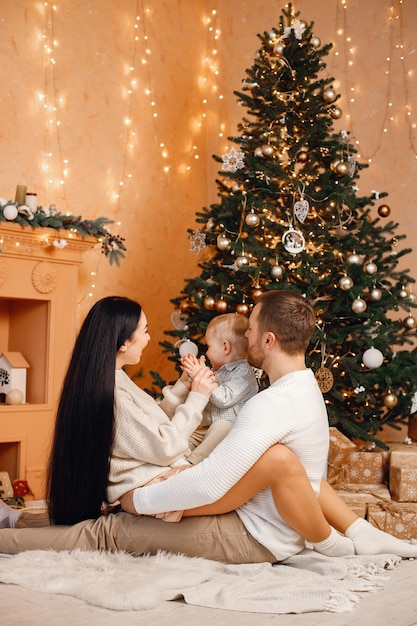 Brunettemuttervater und kleiner Sohn, die nahe Weihnachtsbaum sitzen