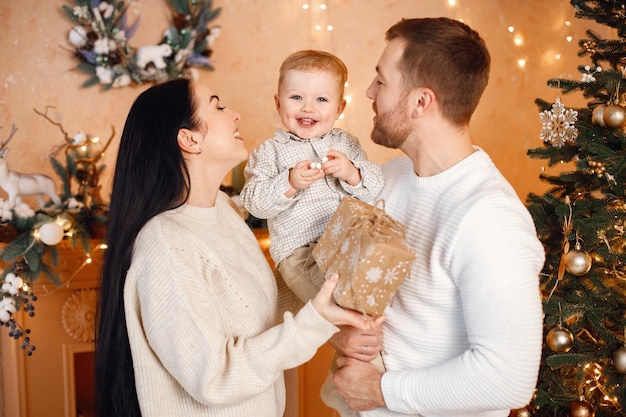 Brunettemuttervater und kleiner Sohn, die nahe Weihnachtsbaum stehen