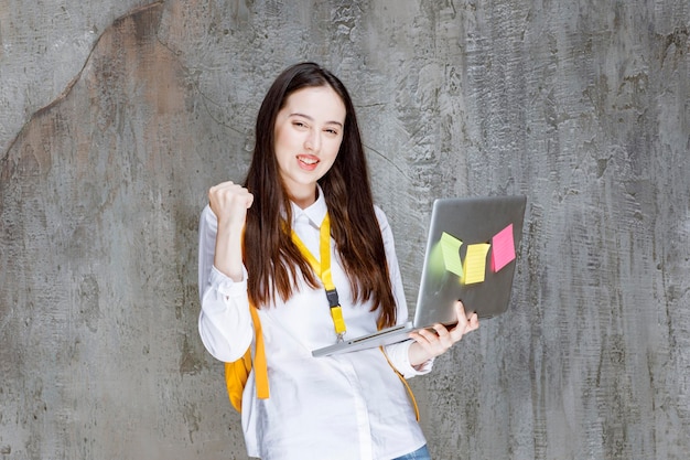 Brunettestudent, der Laptop steht und hält. Foto in hoher Qualität