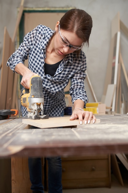 Brunettetischler, der in der Werkstatt mit Laubsäge arbeitet.