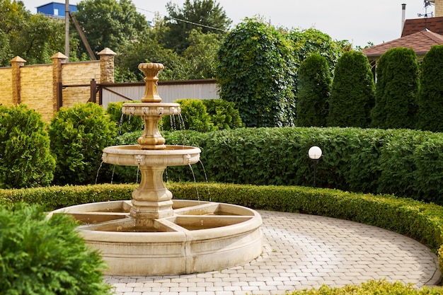 Brunnen mit kleinen Engeln und Dämonen antikem kleinem Wasserfall in der fallenden Tropfennahaufnahme des Gartens