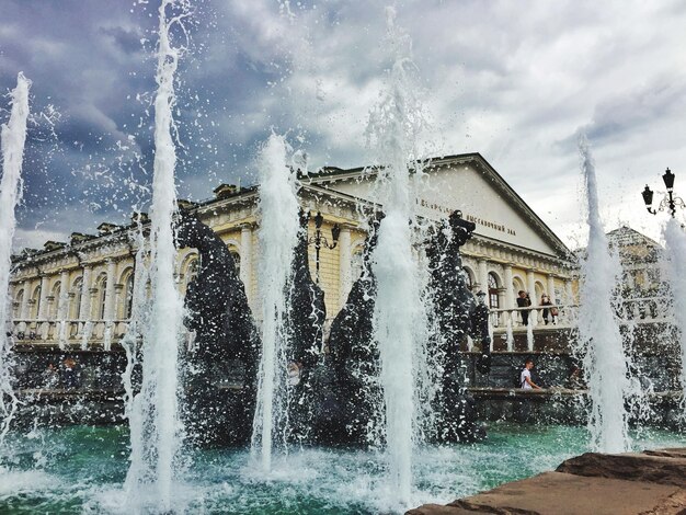 Foto brunnen vor dem gebäude vor einem bewölkten himmel