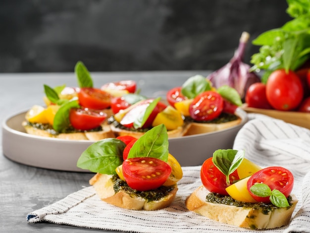 Bruschetta antipasti italiana con tomate, albahaca y pesto sobre una mesa gris Espacio para copiar