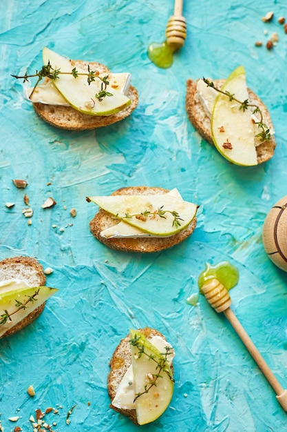 Bruschetta antipasto con queso azul y pera sobre fondo azul.