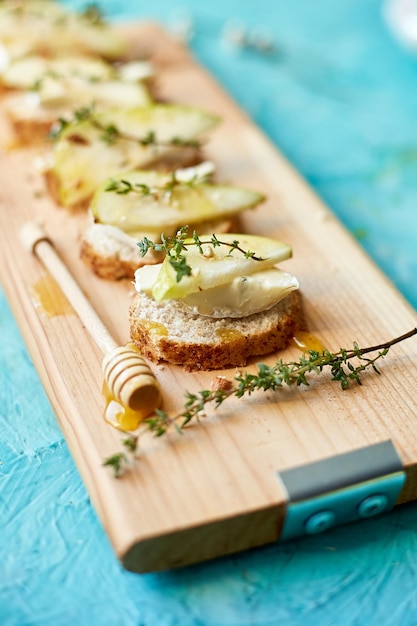 Bruschetta antipasto con queso azul y pera sobre tabla de madera