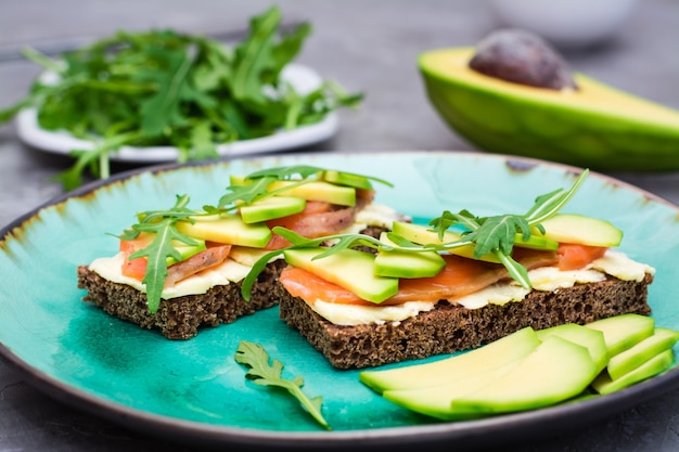 Bruschetta apetitoso com salmão, manteiga, abacate e rúcula em um prato