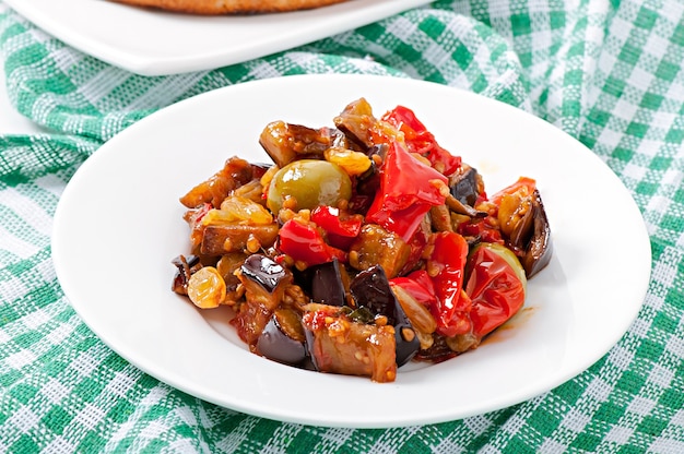 Bruschetta caponata con pasas y piñones decorados con una hoja de albahaca