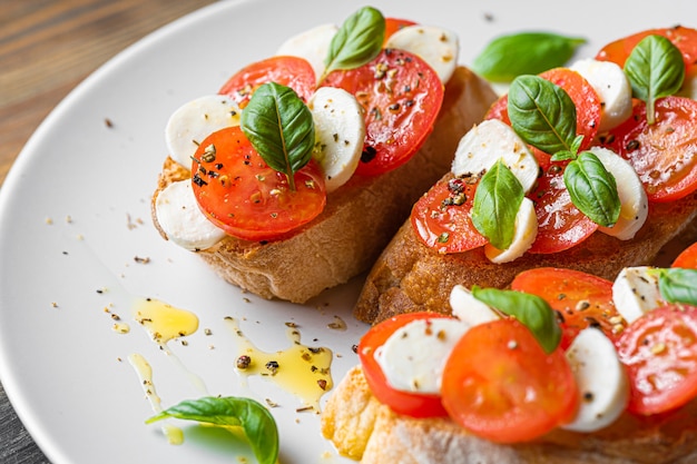 Bruschetta-Caprese. frische Basilikumblätter, reife aromatische Tomaten und italienischer Mozzarella auf Bruschetta, mit Olivenöl beträufelt und mit Pfeffer und Kräutern bestreut.