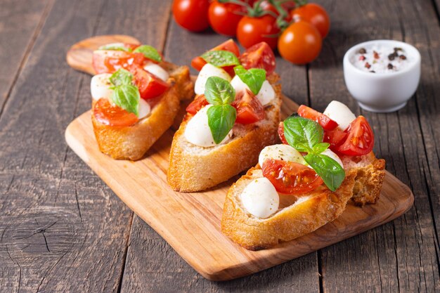 Bruschetta caprese recién hecha con tomate, albahaca y queso. Tapas italianas, antipasti con verduras, él