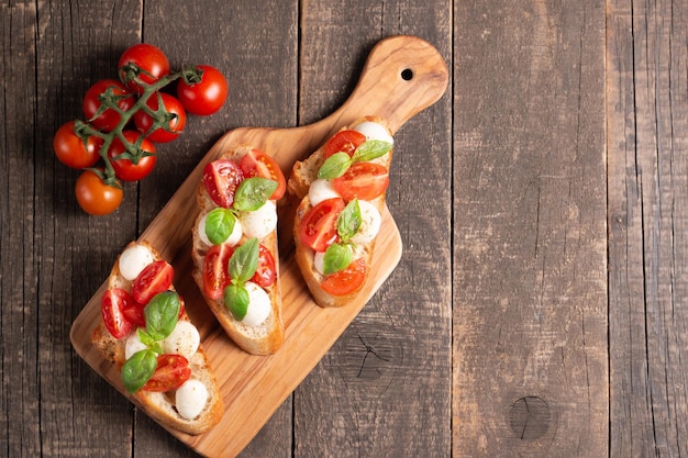 Bruschetta caprese recién hecha con tomate, albahaca y queso. Tapas italianas, antipasti con verduras, él