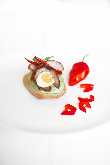 Bruschetta con carne y huevo en un plato blanco sobre un fondo blanco