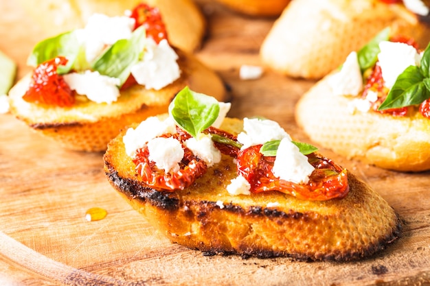 Bruschetta com azeite, tomate seco, queijo feta e manjericão fresco