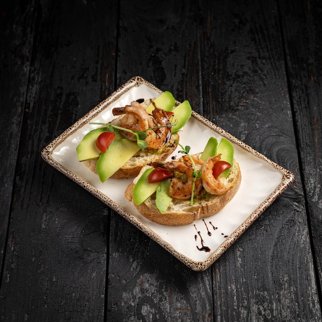 Bruschetta com frutos do mar e verduras em um prato branco.