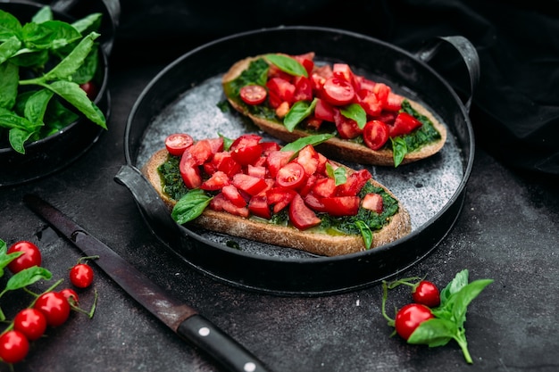 Bruschetta com pesto e tomate em fundo escuro