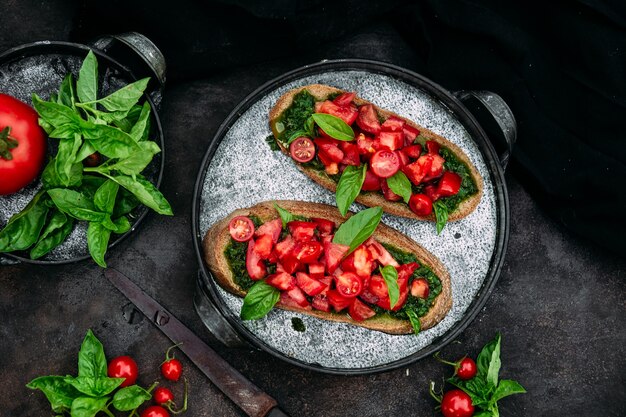 Bruschetta com pesto e tomate em fundo escuro