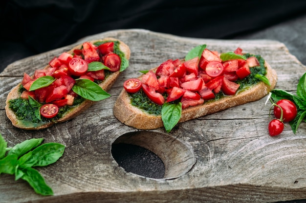 Bruschetta com pesto e tomate em fundo escuro