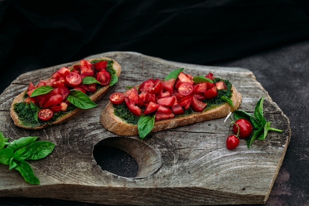 Bruschetta com pesto e tomate em fundo escuro