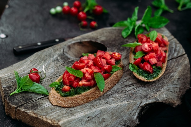 Bruschetta com pesto e tomate em fundo escuro