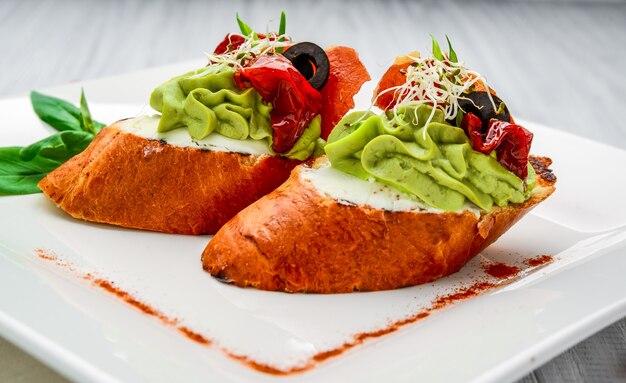 Bruschetta com presunto, abacate, tomate, rúcula e queijo parmesão