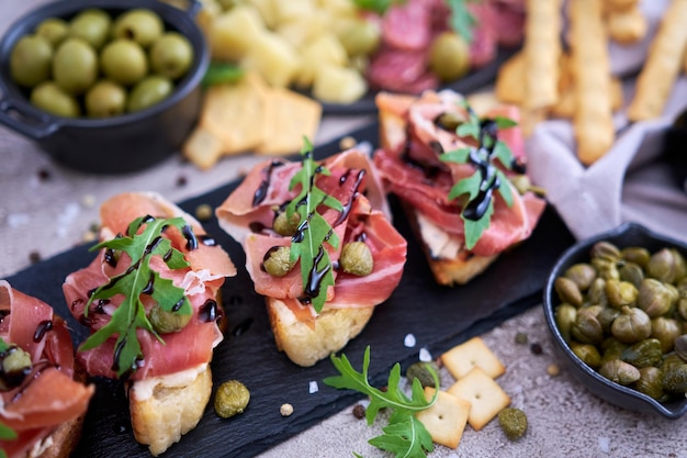 Bruschetta com presunto e alcaparras com prato de carne antepasto tradicional no fundo