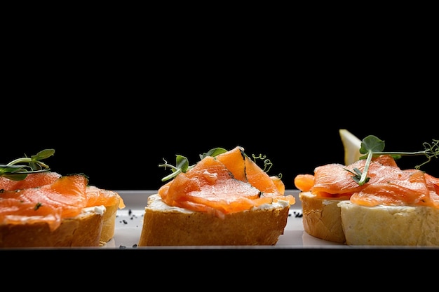 Bruschetta com salmão e manteiga em fundo escuro