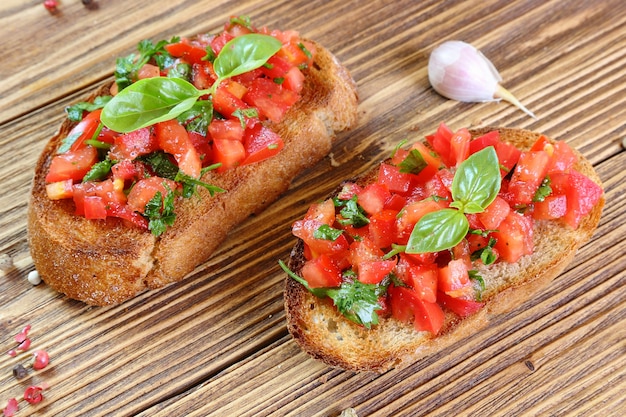 Bruschetta com tomate, alho e manjericão em uma mesa de madeira