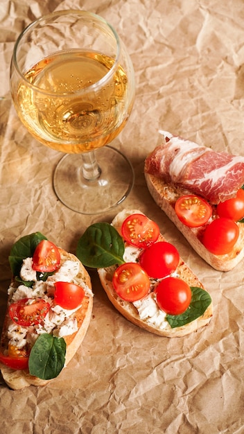 Bruschetta com tomate cereja. Copo de vinho, aperitivo italiano. Fundo de papel artesanal. Conceito de piquenique