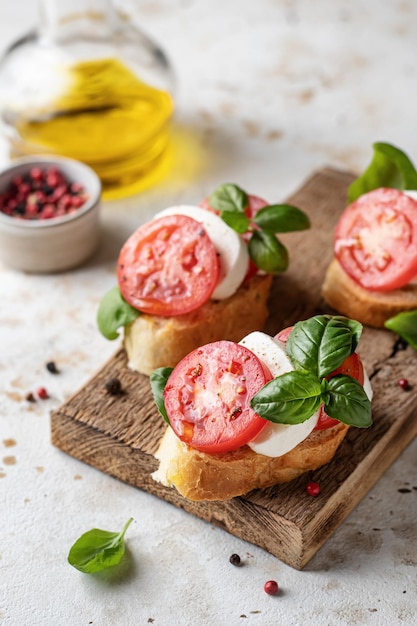 Bruschetta com tomate mussarela e manjericão na placa de madeira com ingredientes