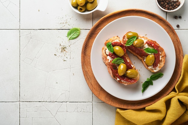 Bruschetta com tomate seco torrada ou sanduíche com ricota tomate seco e ervas de provence com manjericão servido em um prato em uma mesa de azulejos rachado velho cinza vista superior receita de menu de banner