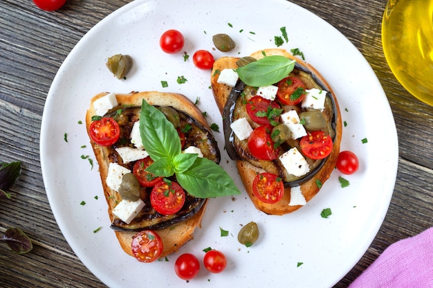 Bruschetta de alho com berinjela, queijo feta, tomate cereja, alcaparras. aperitivo vegetariano útil. cozinha italiana.