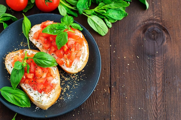 Bruschetta de tomate italiano torrado tradicional com especiarias e manjericão na placa de madeira escura Vista superior com espaço de cópia