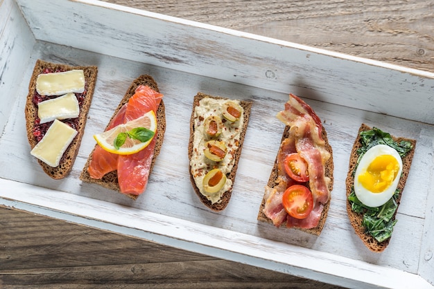 Bruschetta con diferentes ingredientes en la bandeja de madera