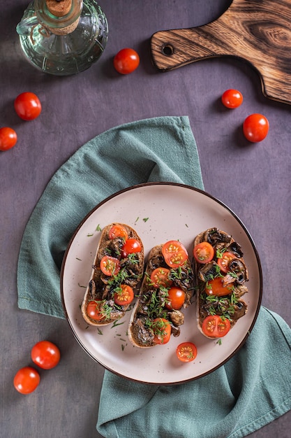 Bruschetta em ciabatta de centeio com tomate cereja e cogumelos fritos em um prato superior e vista vertical