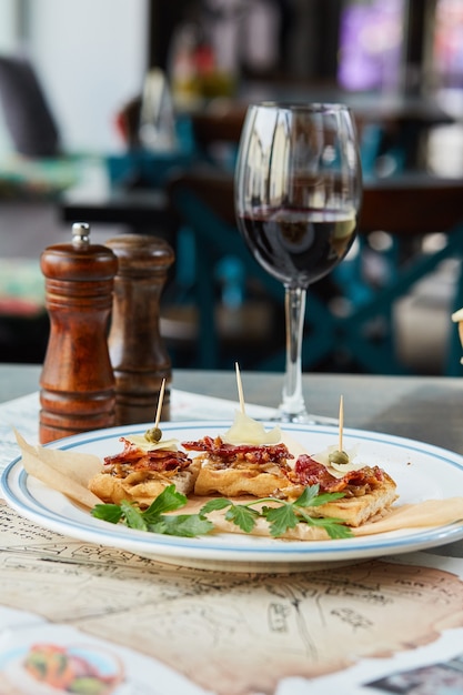 Bruschetta em uma mesa de madeira em um prato branco e uma taça de vinho tinto