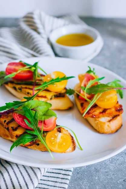 Bruschetta con ensalada de tomate cherry con queso Haloumi a la parrilla, con acelgas y rúcula