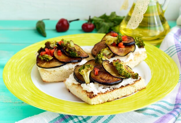 Bruschetta fragante con queso feta, rodajas de berenjena y brócoli a la plancha. De cerca