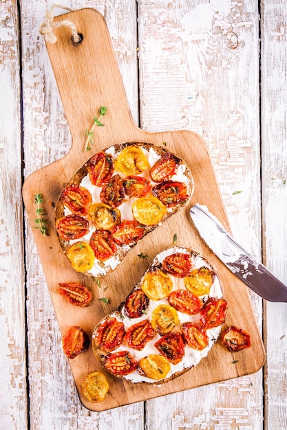 Bruschetta fresca con queso crema y tomates secados al sol sobre una tabla para cortar madera