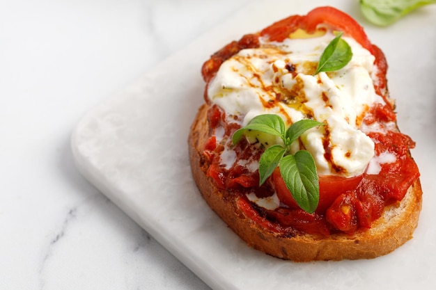 Bruschetta grelhada italiana com queijo stracciatella, tomate, óleo e manjericão Torrada antepasto ou lanche