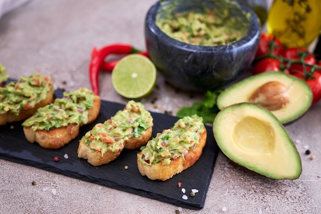 Foto bruschetta con guacamole recién hecho sobre fondo de hormigón gris