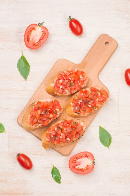 Bruschetta italiana com tomate assado, queijo mussarela e ervas em uma tábua