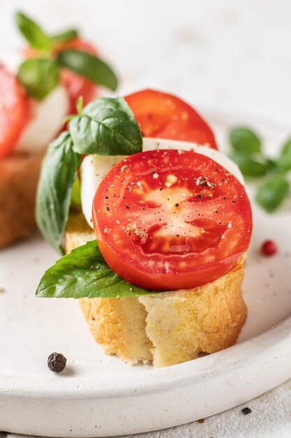 Bruschetta italiana con mozzarella de tomate y albahaca en un plato blanco de cerca