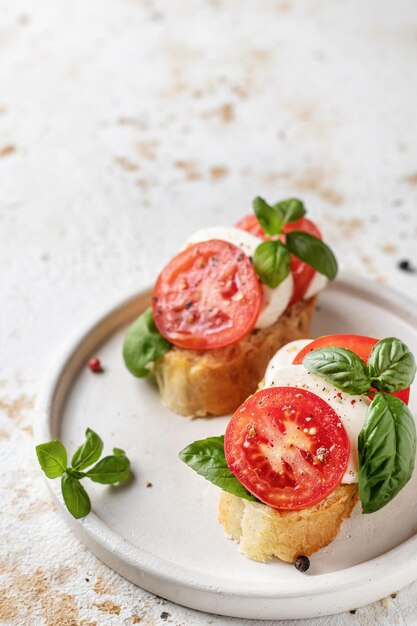 Bruschetta italiana con mozzarella de tomate y albahaca en plato blanco con espacio de texto