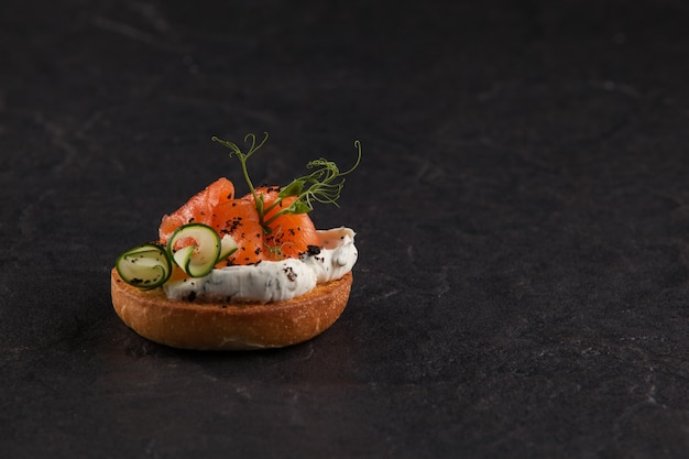 Bruschetta italiana redonda com peixe, tomate, cream cheese e vegetais.